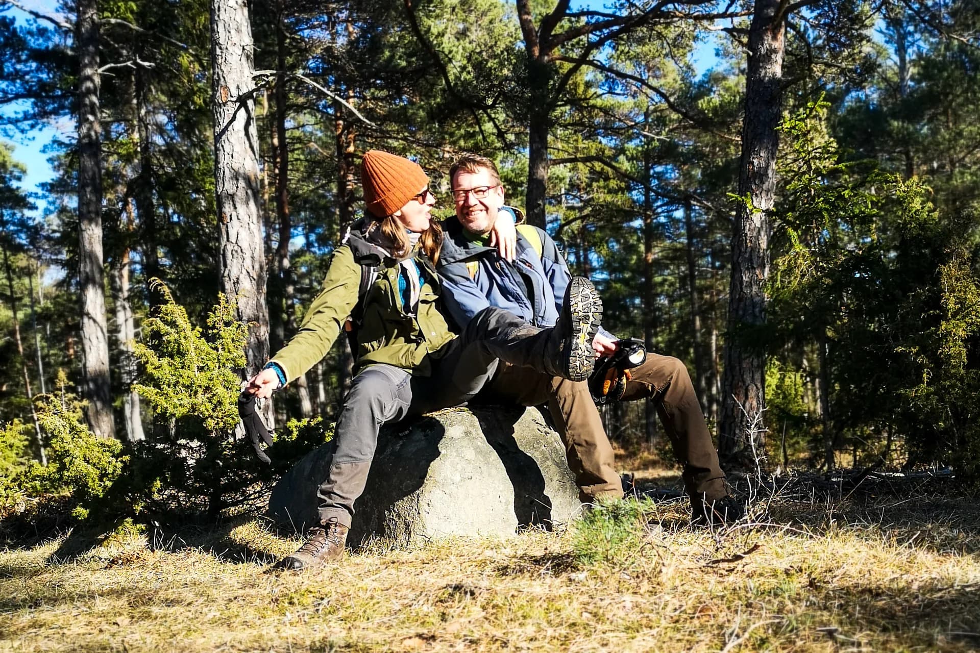 Två personer sitter på sten i skogen